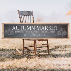 a wooden rocking chair sitting on top of a field next to an autumn market sign