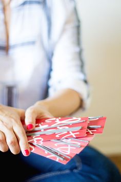 a woman sitting on the floor holding up some red and silver cards with writing on them