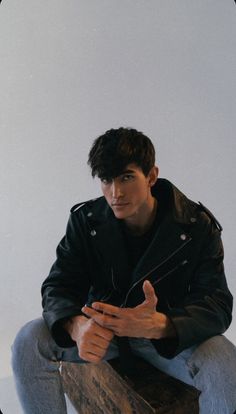 a young man sitting on top of a wooden box holding a cell phone in his hand