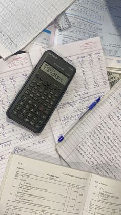 a calculator sitting on top of papers with writing and numbers all over it