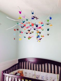 a crib in a baby's room with paper birds hanging from the ceiling