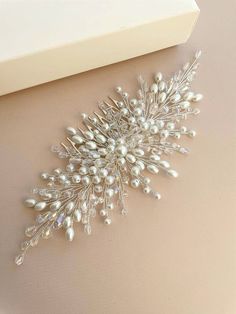 a close up of a brooch with pearls on it's side and a white box in the background