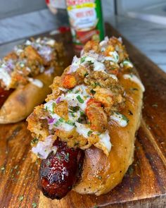 two hot dogs with toppings sitting on a cutting board