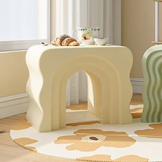 a white table sitting on top of a wooden floor next to a chair and window