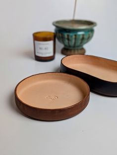 two wooden bowls with lids sitting next to each other on a white counter top, one is empty and the other has a jar in it