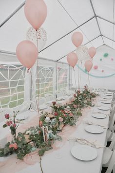 a long table with plates and pink balloons on the top is set up for a party