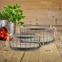 two metal trays sitting on top of a wooden table next to tomatoes and herbs