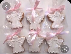 decorated cookies in cellophane bags with pink bows and angel decorations on them,