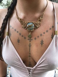 a woman with tattoos on her chest wearing a necklace