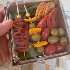 a plastic container filled with lots of different types of vegetables and meat on skewers