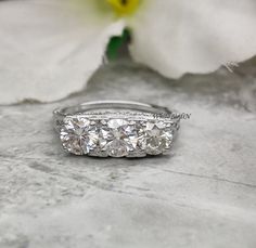 three stone diamond ring sitting on top of a white flower