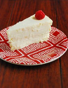 a piece of cake on a red and white plate with a raspberry on top