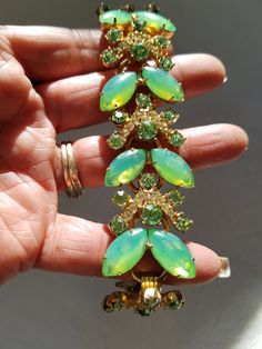 "Featuring this Superb Lime Green Delizza & Elster's AKA \"Juliana\" bracelet from the 1960's. The marquise shaped lime green stones show a glow to them when light shines on them. They resemble a butterfly. Above the two is one round faceted lime green rhinestone, and above that is an upside-down V with pasted clear rhinestones. Some stones are prong set and others are hand pasted. The pattern repeats itself five times. All rhinestones are set in a gold tone setting with a fold over clasp. Back Green Costume Jewelry Bracelets For Party, Vintage Green Bracelets For Party, Green Rhinestone Bracelets For Wedding, Lime Green Gemstone Wedding Jewelry, Adjustable Elegant Lime Green Jewelry, Lime Jewelry, Lime Green Gemstone Ring Jewelry, Fine Jewelry Lime Green Gemstone, Antique Gold Bracelet