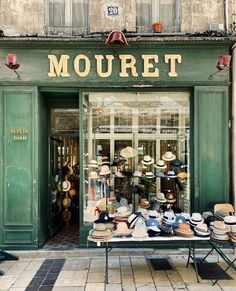 there is a store front with many hats on the table outside and in front of it