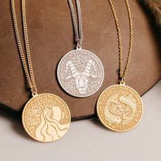 two gold and silver necklaces with zodiac signs on them