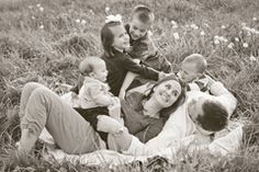 a woman and two children are laying in the grass with their mother on her lap