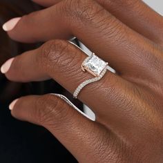 a woman's hand with a diamond ring on top of her finger and an engagement band