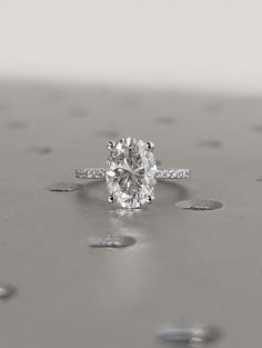 a diamond ring on top of a table with drops of water all around the surface