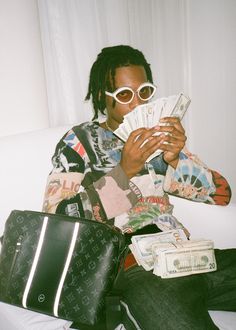 a person sitting on a couch with some money in front of them and wearing sunglasses