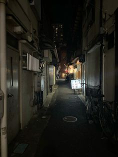 an alley way with bikes parked on both sides and buildings in the background at night