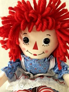 a doll with red hair sitting on top of a table