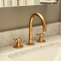 two golden faucets on a white sink in a bathroom