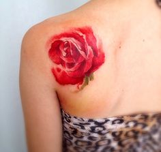 a woman's shoulder with a red rose tattoo on her left shoulder and chest