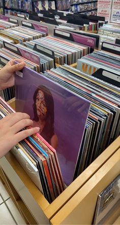 a person holding up a record in front of a shelf full of records at a store