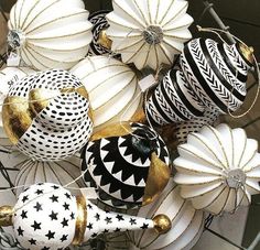 some white and black ornaments are hanging from a wire basket with gold trimmings