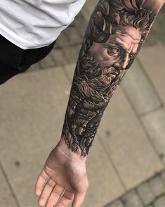 a man's arm with a black and grey tattoo design on the left forearm