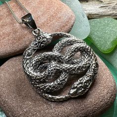 a snake pendant sitting on top of a rock