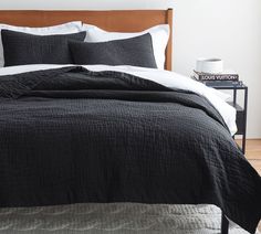 the bed is made with black linens and white sheets, along with two nightstands