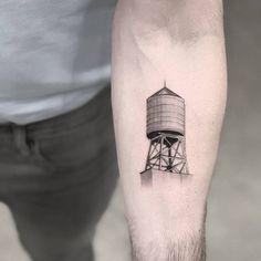 a black and white photo of a man's arm with a water tower tattoo on it