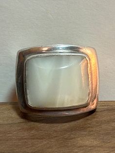 This is a beautiful, vintage, genuine Mother of Pearl /MOP and sterling silver ring. The ring is a size 6 1/2 and easily could be resized if needed larger or smaller. The ring features a rectangular-cut, bezel-set, natural white Mother of Pearl / MOP that is stunning at 5/8" in length by a little less than 5/8" tall or 15.88mm by a little less than 15.8mm. The Mother of Pearl /MOP is high-quality and the ring is very well-made. The ring face measures about 3/4" tall and the sterling silver ring Vintage White Opal Ring For Formal Occasions, Classic White Moonstone Ring In Sterling Silver, Classic Adjustable White Moonstone Ring, Vintage Sterling Silver Hallmarked Opal Ring, Classic White Opal Ring For Gift, Vintage Silver Rectangular Ring, Vintage Sterling Silver Moonstone Ring, White Rectangular Sterling Silver Ring, Vintage White Rings With Polished Finish