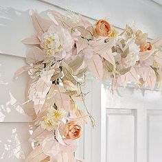 a wreath with flowers hanging from the side of a door