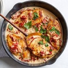 a skillet filled with chicken covered in sauce and garnished with parsley