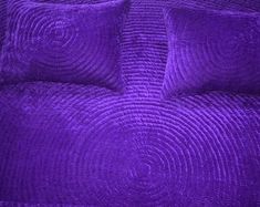 the purple bedspread has four pillows on it