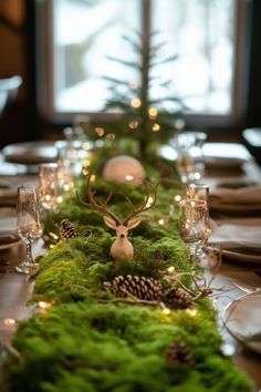 the table is set with moss, pine cones and deer head on top of it