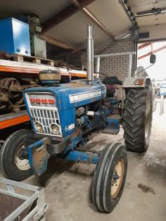 an old blue tractor parked in a garage