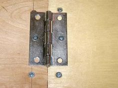 a close up of a door hinge on a wooden surface