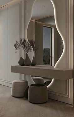 a large mirror sitting on top of a wooden table next to two vases filled with flowers