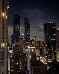 the city skyline is lit up at night, with skyscrapers in the foreground