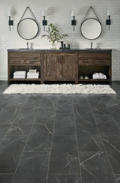 a bathroom with two sinks and mirrors on the wall next to a rug in front of it