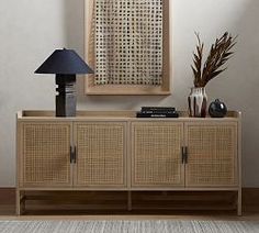 a living room with a lamp and a wicker cabinet in front of the wall