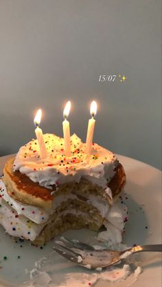 a white plate topped with a cake covered in frosting and lit candles