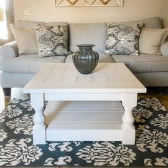 a white coffee table sitting on top of a rug in front of a gray couch