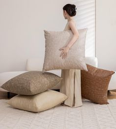 a woman is holding two pillows in front of her