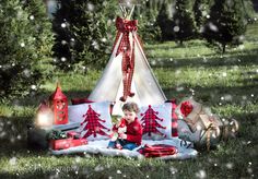 a little boy sitting in front of a teepee tent with christmas decorations on it