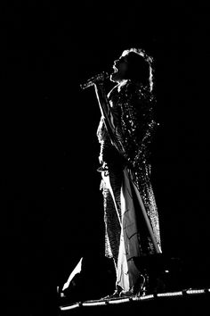 a woman standing on top of a stage holding a microphone in her hand and singing