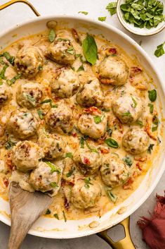 a skillet filled with meatballs covered in sauce and garnished with herbs